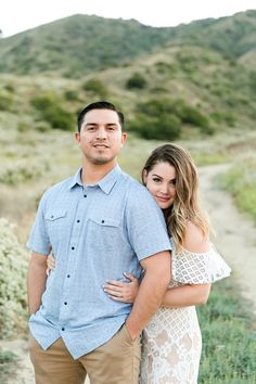 a man and woman standing next to each other on a dirt path in the grass