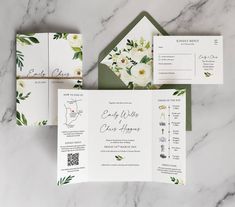 the wedding stationery is laid out on top of the marble table with flowers and greenery