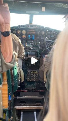 two pilots are sitting in the cockpit of an airplane and one pilot is holding his hand up