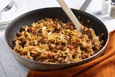 a pan filled with food sitting on top of a table next to a wooden spoon