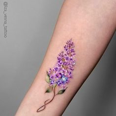 a small purple flower tattoo on the arm