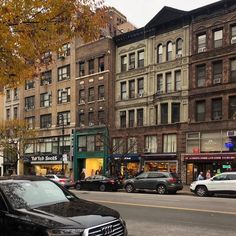 cars are parked on the side of the road in front of tall buildings and shops