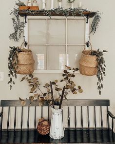 a bench with some plants on it and two baskets hanging from the wall above it