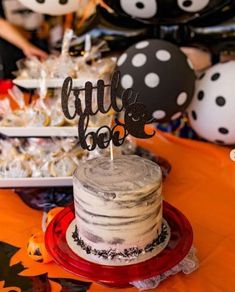 a birthday cake sitting on top of a red plate next to black and white balloons