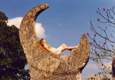 a woman laying on top of a large rock in the shape of a half moon