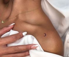 a woman's breast with a small crescent tattoo on her left arm and right hand