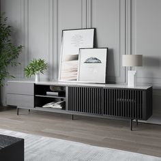 a black and white sideboard with two pictures on it next to a plant in a vase