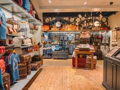 a store filled with lots of different types of clothing and hats on display in front of a wooden floor