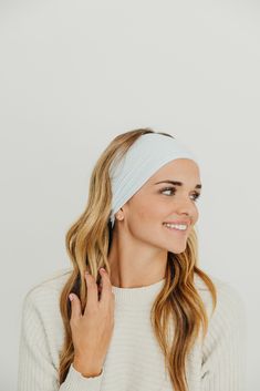 a woman wearing a white headband with her hands on her chest and smiling at the camera