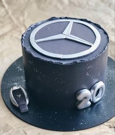 a black cake with a mercedes emblem on it's top and wheels around the edges