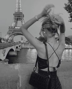 a woman standing in front of the eiffel tower with her hand on her head