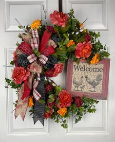 a welcome wreath is hanging on the front door with an old fashioned sign and flowers