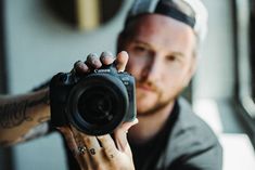 a man holding up a camera in front of his face and looking at the camera