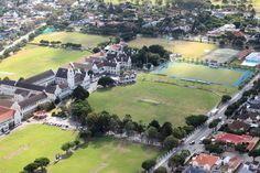 an aerial view of a large tennis court and buildings in the distance with trees on both sides