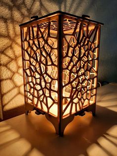 a lit candle holder sitting on top of a table next to a shadow cast wall