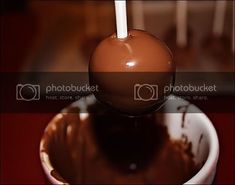 a chocolate candy with a white stick sticking out of it's center in a bowl