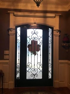 the front door is decorated with wrought iron doors and glass panels, along with a chandelier