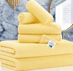 yellow towels stacked on top of each other in front of a mirror