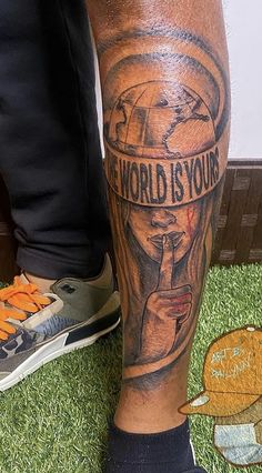 a man with a tattoo on his leg that says the world is yours