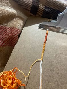 an orange and white string is attached to the handle of a hairdryer on a couch