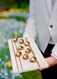 a person holding a tray with small appetizers on it