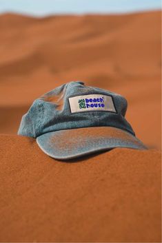 a blue hat sitting on top of a sand dune in the desert with words written on it