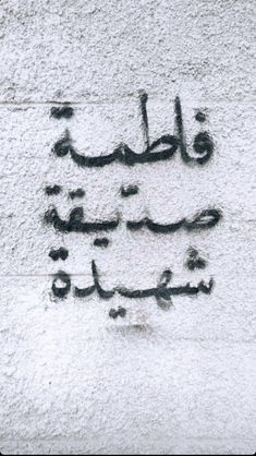 arabic writing on the side of a building in an old town, with black ink