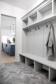 a white coat rack with two coats hanging on it's hooks and some towels