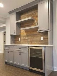 an empty kitchen with gray cabinets and wood flooring in the middle of the room