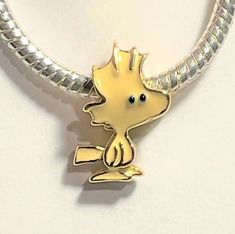 a yellow and silver charm with a small cartoon character on it's back end