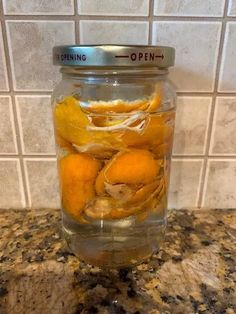 a jar filled with orange peels sitting on top of a counter next to a tile wall