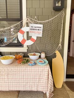 a table topped with bowls of food next to a hammock hanging from the wall