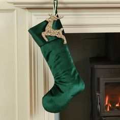 a green christmas stocking hanging from a fireplace with a deer decoration on it's side