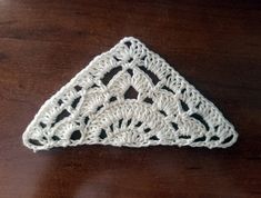 a white crocheted triangle sitting on top of a wooden table