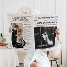 a woman sitting on the floor holding up a newspaper with an image of a couple kissing