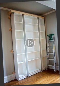 an empty room with white bookcases and a ladder in the corner next to it