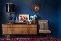 a room with blue walls and a wooden dresser topped with vases filled with flowers