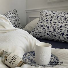 a bottle of whiskey sitting on top of a bed next to a cup and saucer