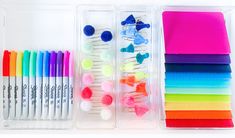 several different colored pens and markers in a plastic container with dividers on the side