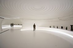 a man standing in the middle of a room filled with white walls and flooring