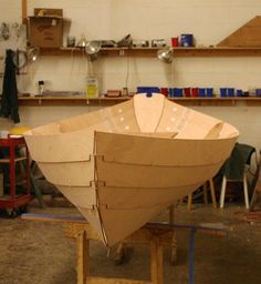 a wooden boat sitting on top of a table in a room filled with shelves and tools