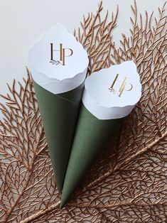 two green cones with gold monogrammed letters on them sitting next to each other