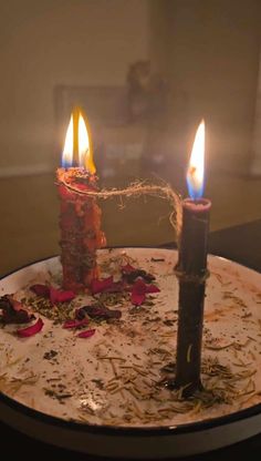 two lit candles sitting on top of a plate