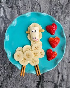 a plate with bananas, strawberries and a sheep made out of fruit on it