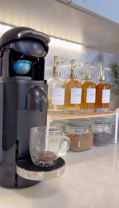 a coffee maker sitting on top of a counter next to cups and jars filled with liquid