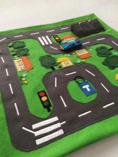 a play mat with cars and traffic lights on the road in front of a toy car