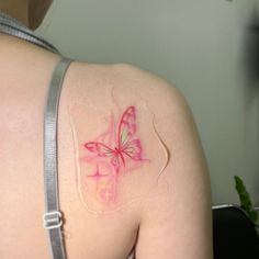 the back of a woman's shoulder with a pink butterfly on it