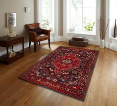 a living room with hardwood floors and white walls, has a red rug on the floor