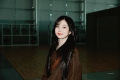 a woman with long black hair standing in an empty room