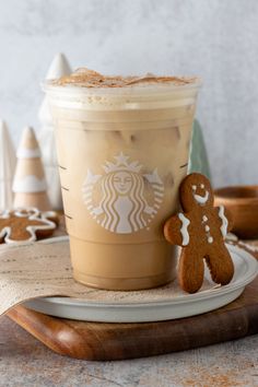 a cup of coffee and a gingerbread cookie on a wooden tray next to it